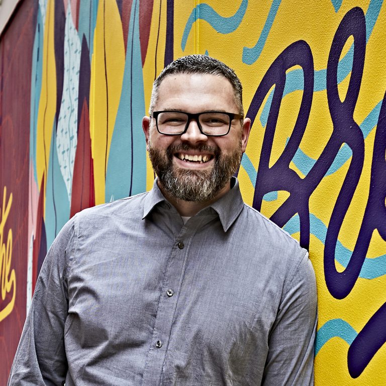 Zach smiling in front of mural