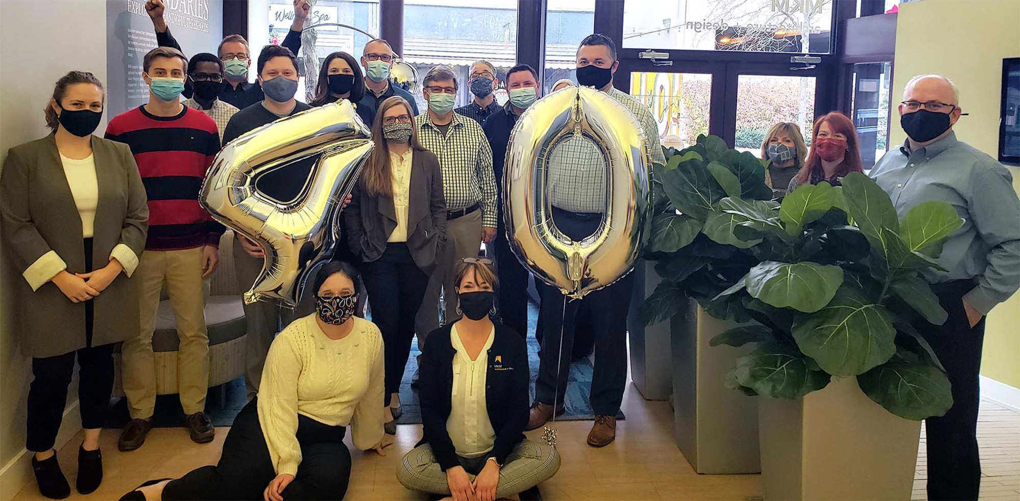 MKM staff members pose with a number four and a number zero balloon