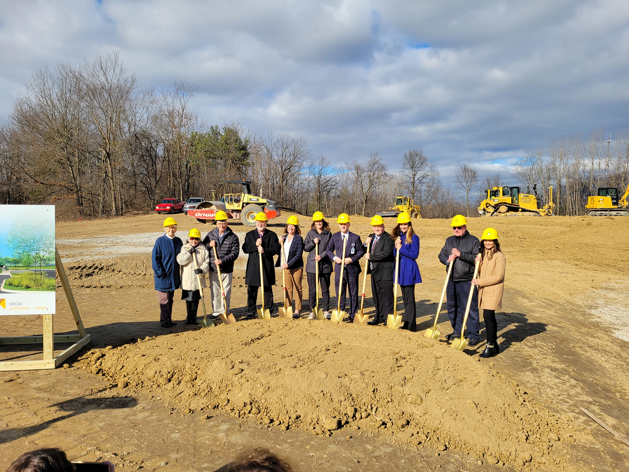 people standing on dirt site with shovels in yellow hard hats