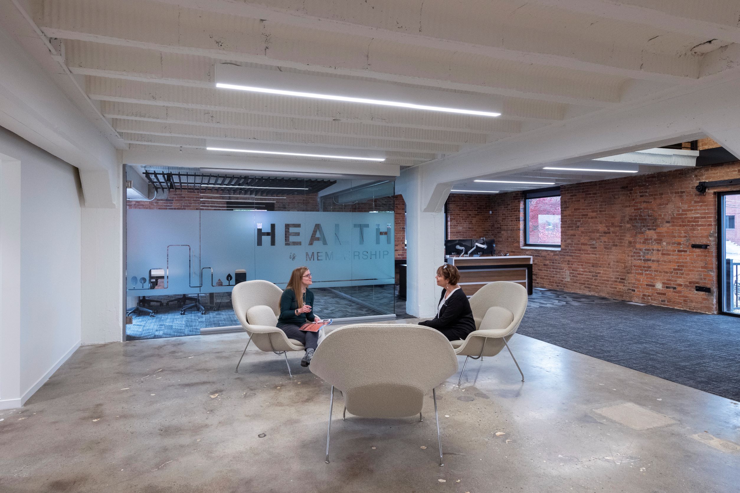 Two women sitting in white chairs having a conversation