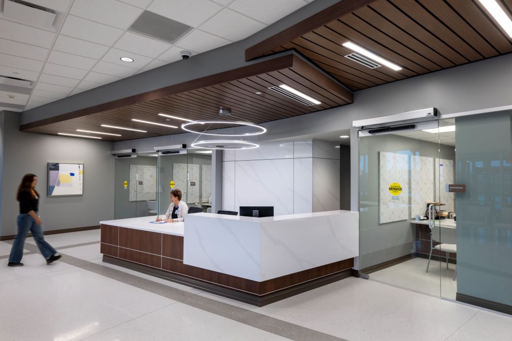 woman walking towards a reception desk and smiling worker