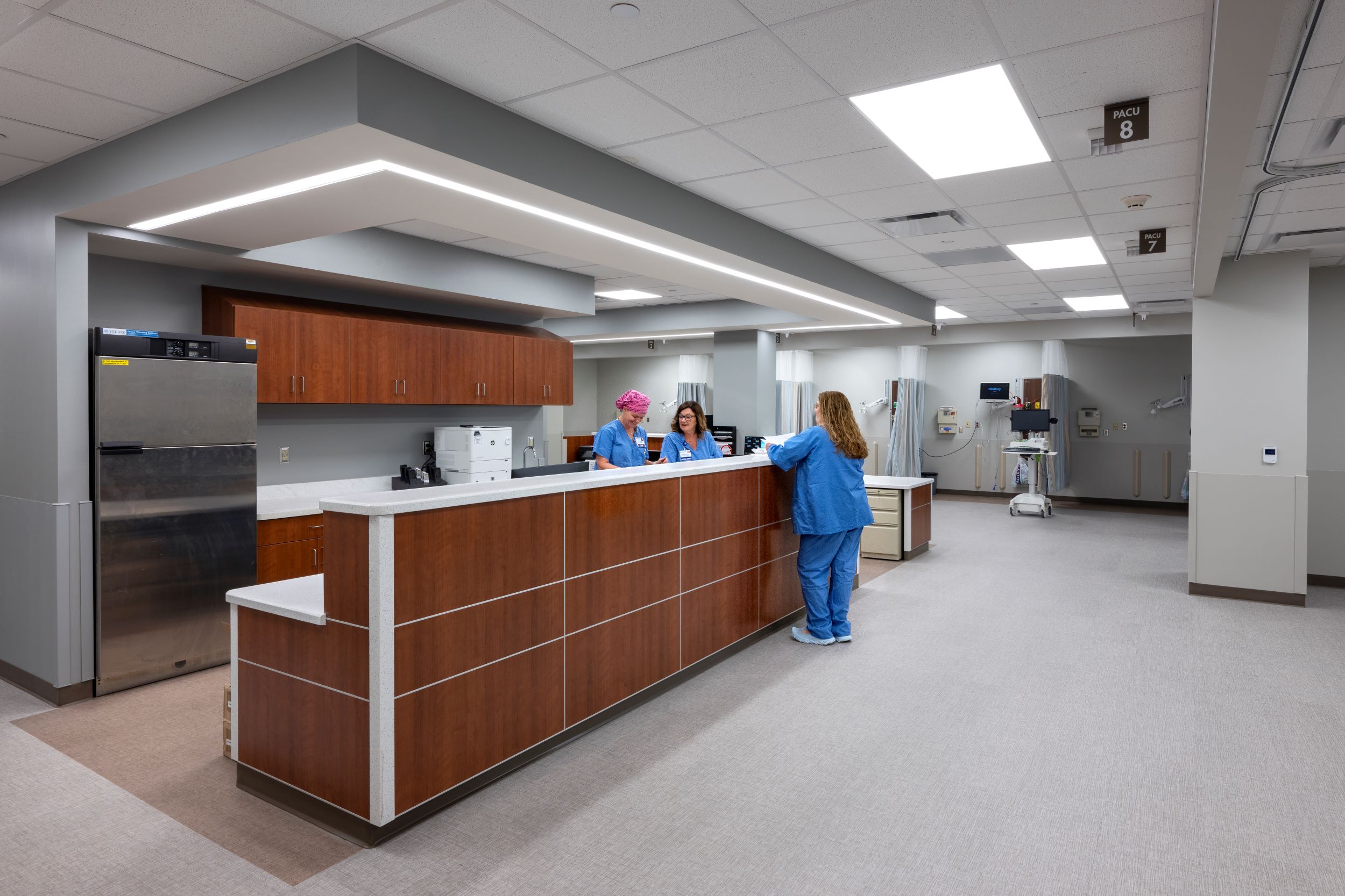 three nurses standing at central desk