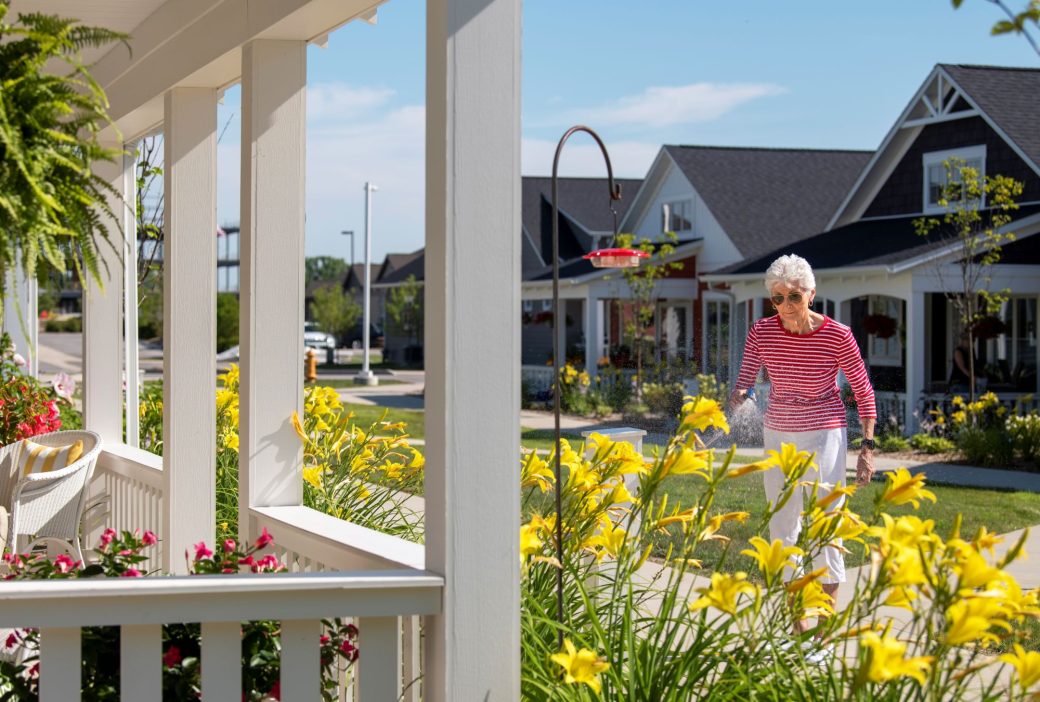 Piper Trail outdoor woman in striped shirt watering yellow flowers